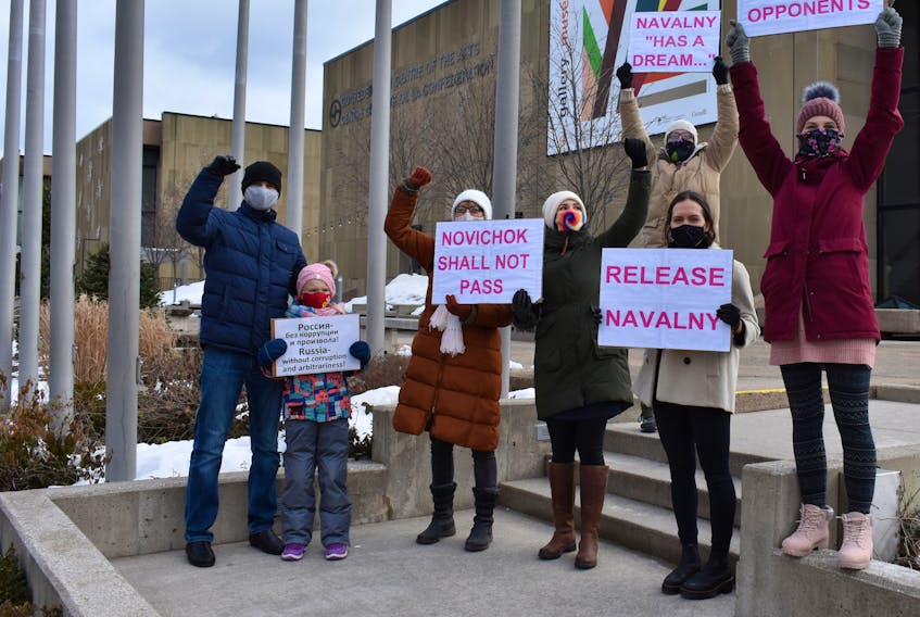 Protestors hold up signs at a small demonstration in downtown Charlottetown on Saturday. Sporadically, they called out "release Navalny."