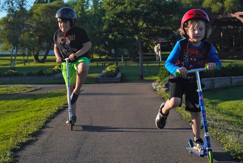 Owen Toms, 7, pulls off a scooter balancing trick while his brother, Callum, 5, scoots by at the A.A. MacDonald Memorial Park in Georgetown on a sunny day last month.