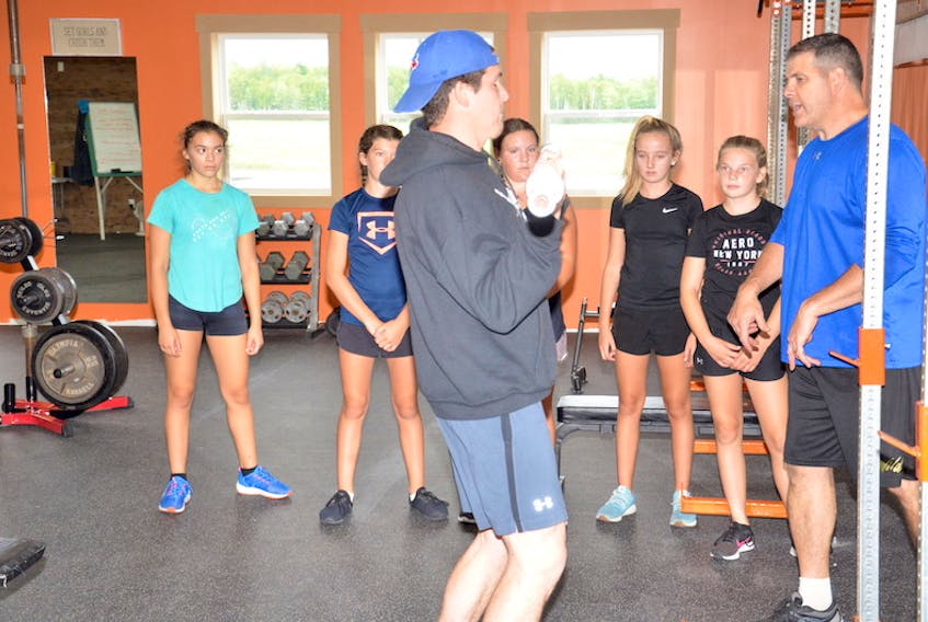 Jacob Arsenault demonstrates an exercise while Brian Arsenault instructs the group of young athletes during a recent training session at Rte. 2 Success in Richmond.