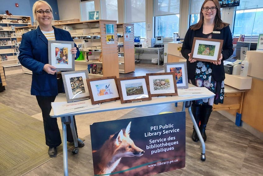 Lori Ellis, left, of Wyatt Heritage Properties Inc. and Culture Summerside and Rebecca Boulter, regional librarian with Summerside Rotary Library, look over some of the original art work that can now be borrowed at the library.