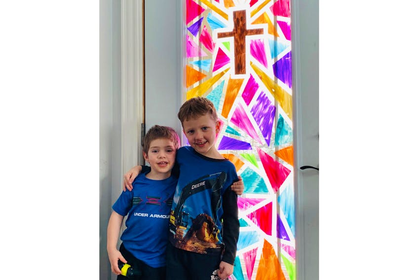 Two of Jackie and Alex LeClair’s five children, A.J., left, 3, and Caleb, 6, are pretty proud of the job they did on the front door of their house in Tignish. Residents throughout the community have been keeping their kids busy painting windows and glass doors the colour of stained-glass windows in churches as Easter approaches.