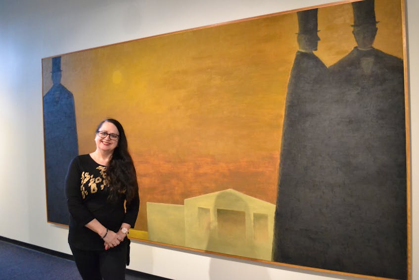 Debbie Muttart stands next to Charlottetown Revisited, 1964. The painting by Jean Paul Lemieux is part of The Debbie Show, an exhibition currently running at the Confederation Centre Art Gallery.