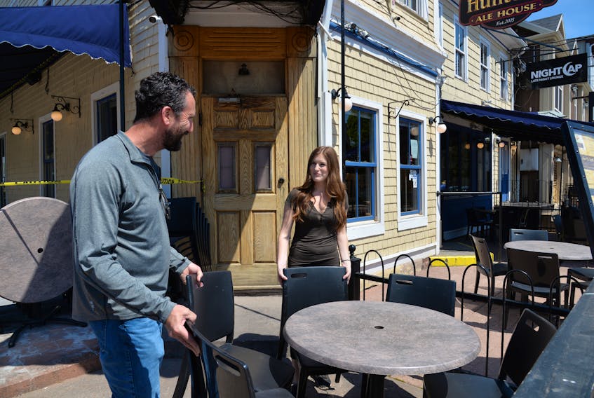 Jeff Sinnott, left, co-owner of the Red Island Hospitality Group Inc., and Hailey McDonald, events co-ordinator, set up the patio on Thursday at Hunter's Ale House in Charlottetown in anticipation of Monday's reopening of dining and patio services.