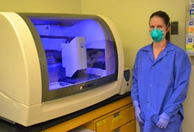 Kari-Lyn Ratley, a medical laboratory technologist, stands next to the BD Max System, which can provide results for up to 24 COVID-19 test tests within three hours.