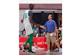 Boston Celtics assistant coach Scott Morrison, right, meets rookie Tacko Fall at the bench.