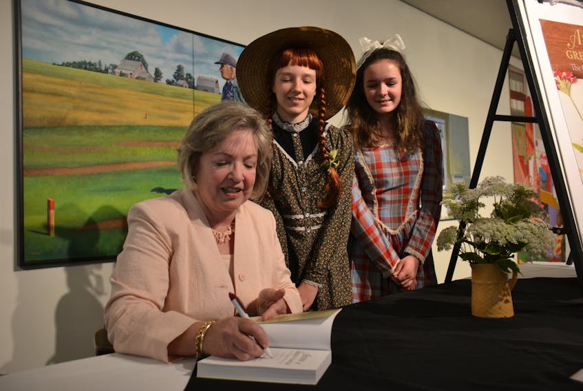 Carolyn Strom Collins, left, signs a copy of her new book, "Anne of Green Gables: The Original Manuscript", during the launch event at the Confederation Centre of the Arts in Charlottetown on Aug. 1. Dressed as the book’s main characters, Anne Shirley and Diana Barry, are Nadia Milewski and Rilla Bruce.