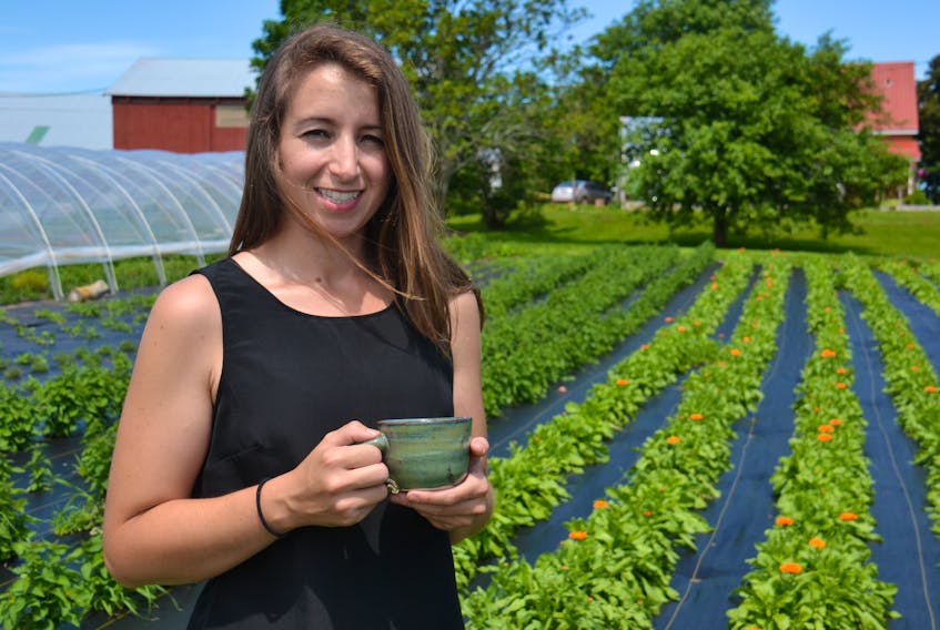 Janell MacDonald enjoys a cup of tea in her garden at the New Argyle Farmery. Behind her are many plants, like calendula, anise hyssop, oregano, thyme and sage.