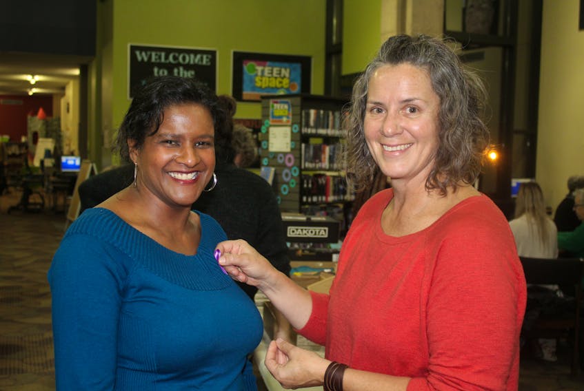 Deborah Langston, left, chairwoman for the P.E.I. Advisory Council on the Status of Women, receives her purple ribbon from Michelle Jay, program co-ordinator for the P.E.I. Advisory Council on the Status of Women, at their pinning bee event at the Confederation Centre Public Library on Tuesday, Nov. 5.