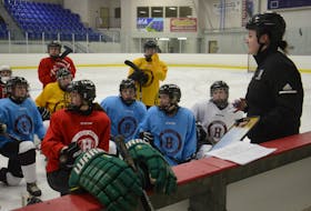 Head coach Jess Cameron, right, listens to a question at the Holland College Hurricanes practice Wednesday in Three Rivers.