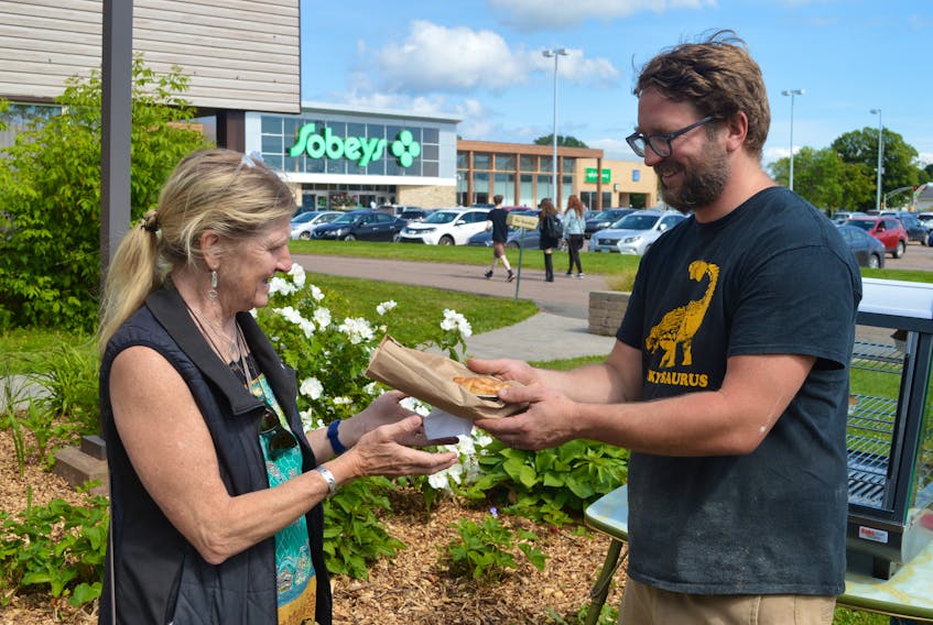 Scottie Miller, Kiwi Kai P.E.I., hands one of his New Zealand pies over to Christine Loock-Friesen of British Columbia at the Thursday Pop-up Market at the Farm Centre in Charlottetown on Thursday. Miller is one of about a dozen local vendors that takes part in the market that operates every Thursday, 3-6 p.m.