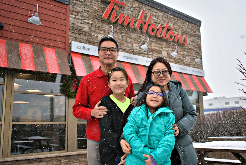 Victor and Olivia Chu with their daughters' Victoria, from left, and Chloe enjoying their first Canadian winter outside of one of their favourite fast-food restaurants, no other than Tim Hortons.