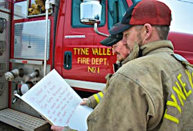 Daniel Grigg, from left, and Andrew Morrison of the Tyne Valley Fire Department read a large ‘thank you’ card written by the Tyne Valley Tornadoes Peewee A boys hockey team. The young hockey team played many games at the Tyne Valley Community Sports Centre and came early Saturday morning to show their support.