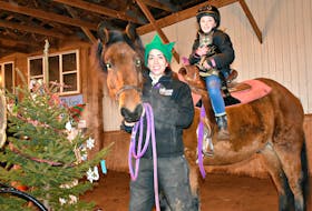 Jasmine Bastarache holds Jack, the horse, while confident rider Ella Campbell and her cat Pepper go for a ride around the barn.