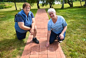 Colette Gallant, from the left, and her sister Jeannette Arsenault remember loved ones on the Path of Remembrance during the annual International Children’s Memorial Place bricklaying ceremony, held Sunday afternoon.