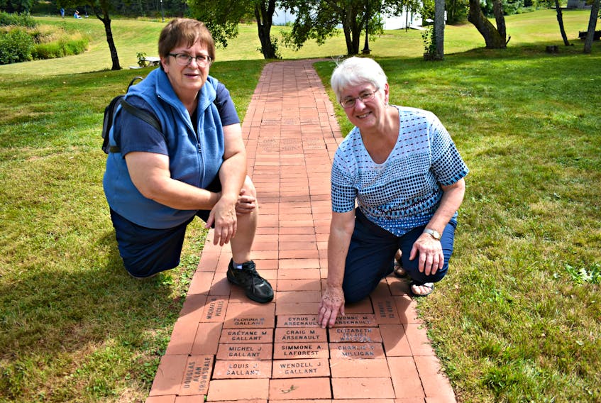 Colette Gallant, from the left, and her sister Jeannette Arsenault remember loved ones on the Path of Remembrance during the annual International Children’s Memorial Place bricklaying ceremony, held Sunday afternoon.
