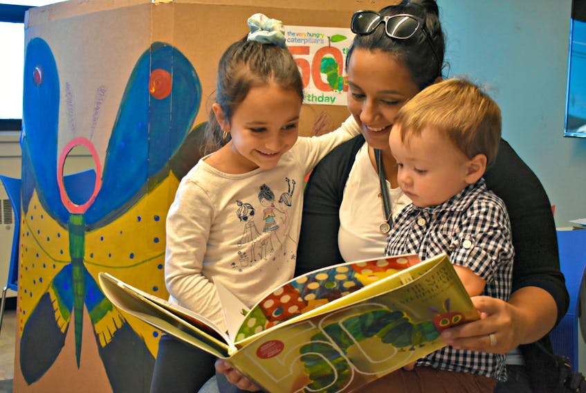 Julie Salvador reads a special edition of Eric Carle’s ‘The Very Hungry Caterpillar’ to her two children Olivia MacKendrick and Teddy Smith.