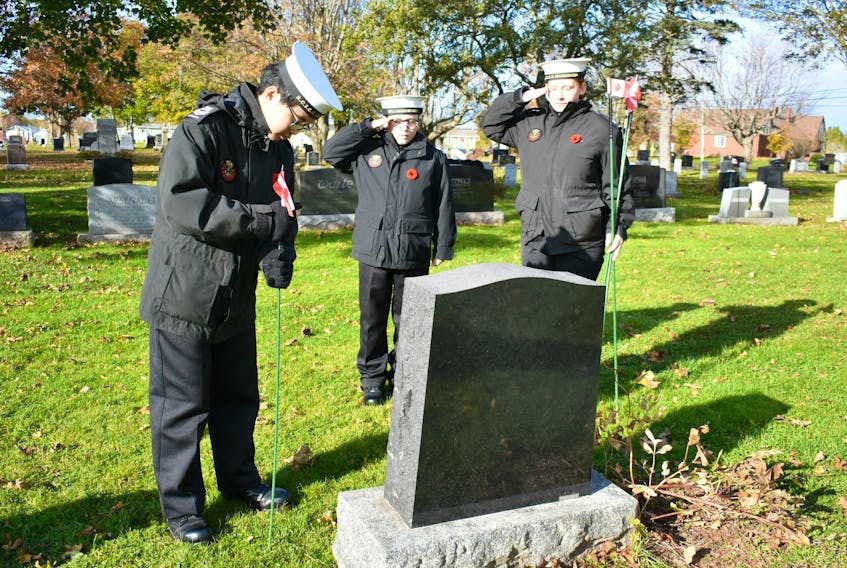 RCSCC Summerside Sea Cadet Corps Annie Sham, from left, Evan Smith, and Grace Smith mark a veteran’s headstone with a small Canadian flag to honour and remember their service.
