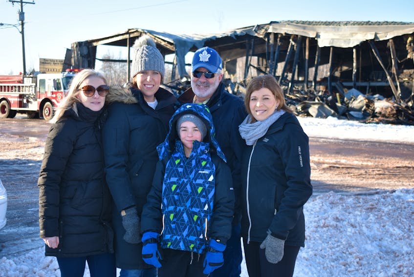 Chantel Noye, from left, Crystal MacKendrick, Ronnie Mackendrick, Bryan MacKendrick, and Amy MacKendrick watch as the last hot spots are doused and the black smoke wafting through the remaining steel frame of the Tyne Valley Community Sports Centre is tamed by firefighters.