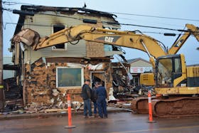 Members of a demolition crew confer in front of the burned-out remains of Eugene’s General Store. A crew from Northern Enterprises demolished and commenced trucking away the remains of Tignish’s landmark store on Tuesday.