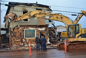 Members of a demolition crew confer in front of the burned-out remains of Eugene’s General Store. A crew from Northern Enterprises demolished and commenced trucking away the remains of Tignish’s landmark store on Tuesday.