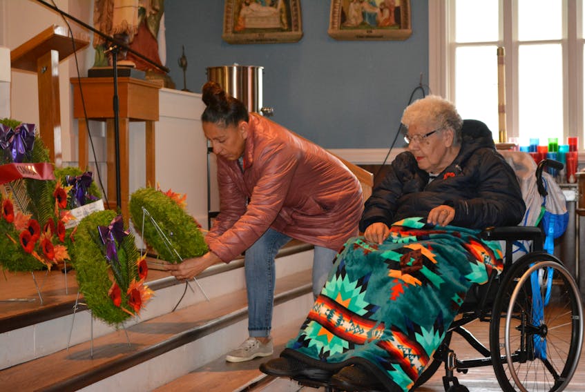 Kate Arsenault assists Theresa Lewis in laying a wreath for Motherhood, during a Service of Remembrance at St. Anne’s Church, Lennox Island on Remembrance Day.