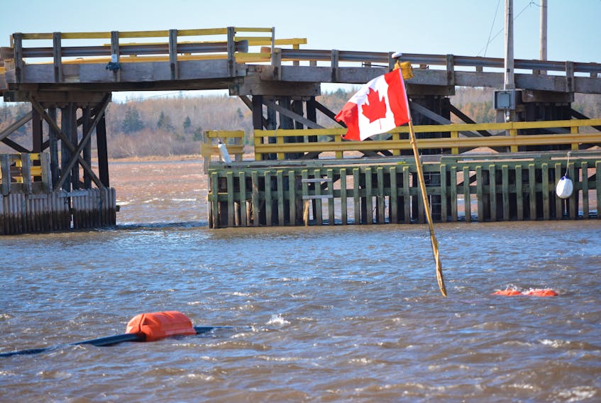 A Canadian flag flies on the telescopic pole that marks the position of a robotic dredge at work in the Skinners Pond Harbour basin.