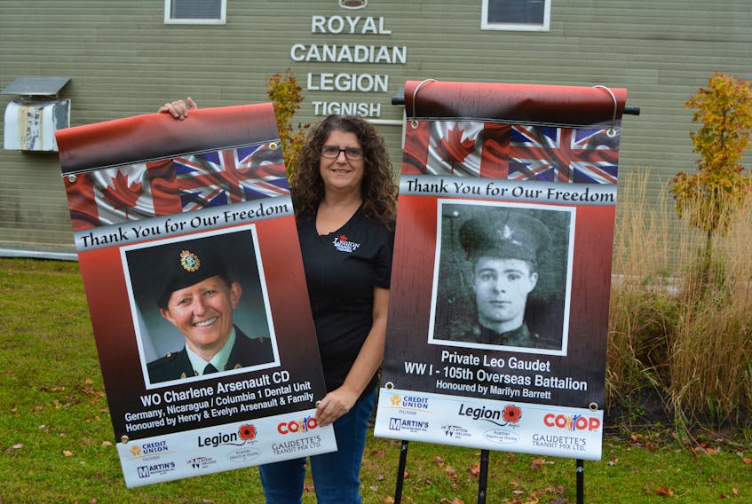 Stephanie Kinch, a co-ordinator of the Tignish Legion’s Remembrance Banner project, displays two of the 76 banners that will be suspended from posts around the legion parking lot until after Remembrance Day.
