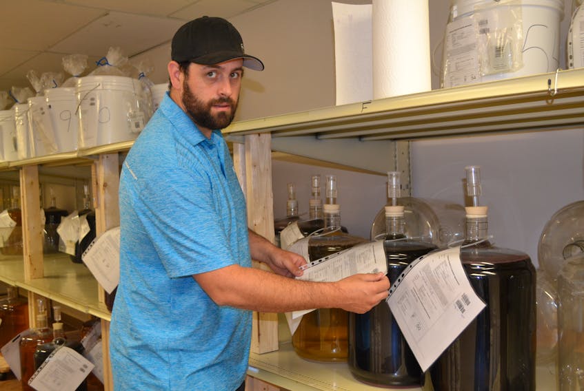 Chris Trail, owner of The Cork and Barrel Homebrew Shop, checks the progress on customer’s wine kits he is brewing in his shop located in the Bloomfield Mall. Trail has turned a beer and wine-making hobby into a business.