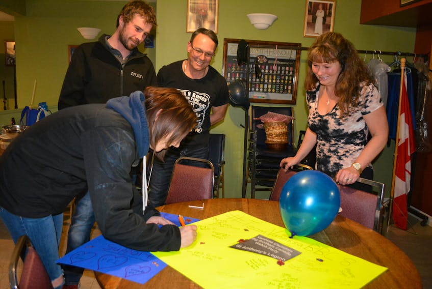 Emily Ramsay adds her message to a poster wishing Vanessa Clements well in the Big Brother Canada house. From left, Mike MacLean and Blair and Cindy Clements.