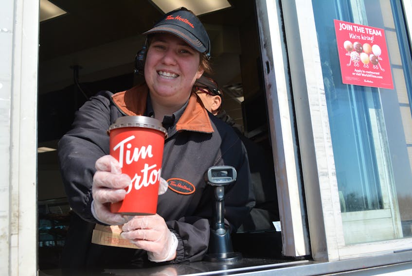 Julia O‘Halloran staffs the drive-thru window at the O’Leary Corner Tim Hortons restaurant. It’s business as usual at the drive-thru window, but the national chain has temporarily closed all of its dining rooms. While customers can still go inside to pick up takeout orders, most seem to prefer the drive-thru line.