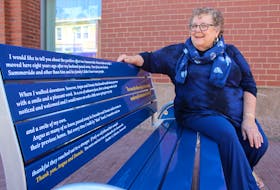 Heather Johnston takes the first sit on a new buddy bench being installed in downtown Summerside. The bench commemorates Angus and Donnie MacDonald and has part of a letter to the editor written on it, in which Johnston thanked the brothers for their welcoming nature.
