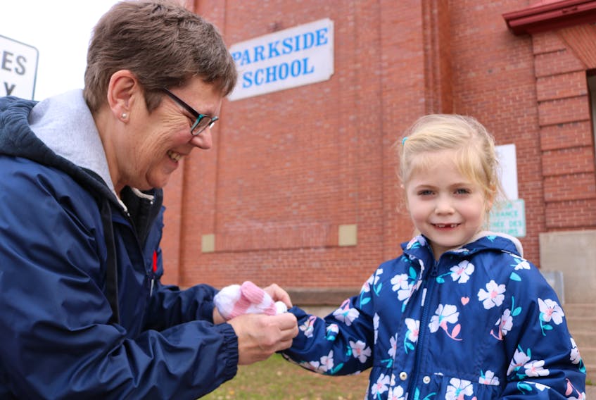 Susan Perry, left, warms up Elliotte Lynch's cold hand with a pair of mitts she recently made. Elliotte is a kindergarten student at Parkside Elementary School in Summerside.