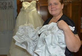 Mindy Ashwood shows some of the angel dresses she has made to date. In the background is a wedding dress, which was never worn and still has its tags, that was donated by a woman who suffered a miscarriage and who wants her dress turned into angel dresses.