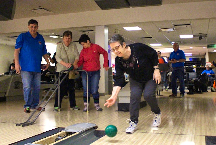 Sandra Poirier, centre, bowls as participants of the annual bowling event to mark White Cane Week watch.