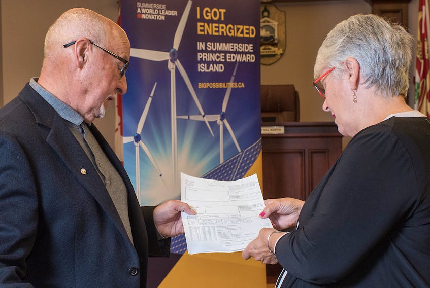 Summerside Mayor Bill Martin and provincial Energy Minister Paula Biggar review a utility bill showing the 10 per provincial rebate for Summerside power customers.