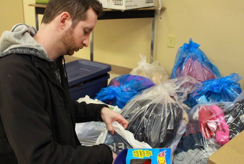 Dan Harding looks through a bag of donated clothes and toys after a fire destroyed his family’s home in Slemon Park.