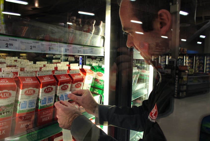 Jamie MacPhail, ADL marketing manager, adds a sticker to a carton of ADL brand milk indicating it is made entirely with P.E.I. dairy products.