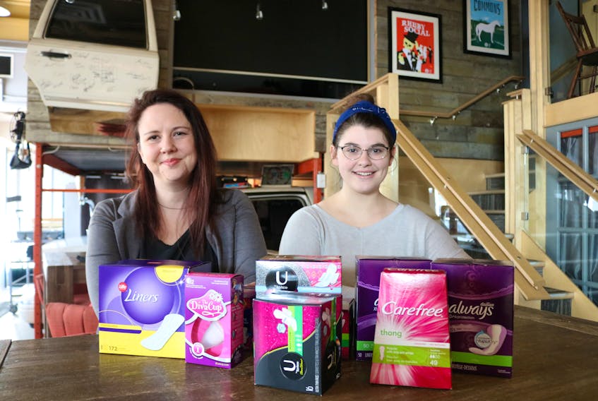 Megan Bearisto, left, and Kassidy Arsenault read about a menstrual cup. The pair have started the Facebook group ‘No Questions Asked. Period.’ in hopes of creating a supporting community for people with periods as well as aid in the procurement of feminine products for those who may not be able to afford them.