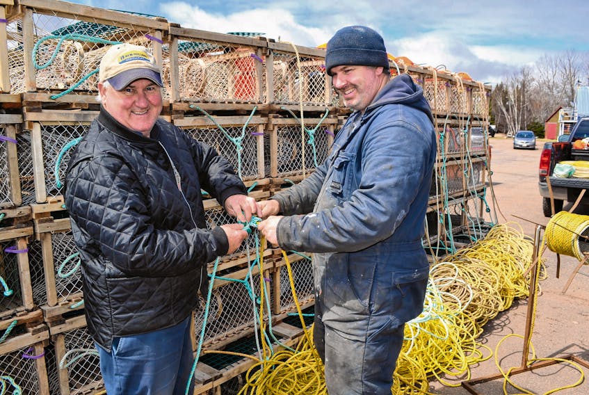 Captain Stephen Smith, right, gets help from his father, retired fisherman William Smith, in tying on trap lines at Milligan's Wharf. They are getting ready for the spring lobster fishery which, following a delay announced on Saturday, is now scheduled to start Tuesday if weather permits.