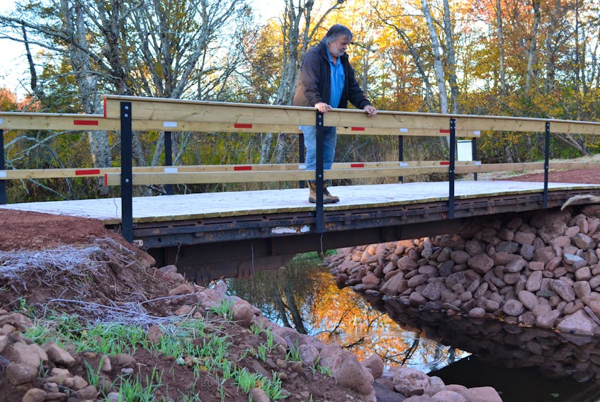 Elton Ellis, co-ordinator of West Point and Area Watershed Association, checks the water flow beneath a new bridge deck his association recently installed with help from volunteers and the Wildlife Conservation Fund.