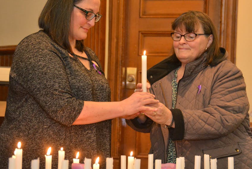 Nancy Beth Guptill, left,  and Gloria Schurman light a candle in memory of one of the 14 victims of the 1989 École Polytechnique massacre.