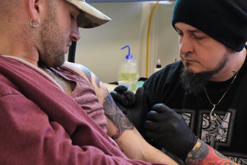 Aron Scott, right, works on Josh Gallant’s freshly inked upper arm. Scott, Griffen Dunsmore and Oliver Wassef are the new owners of a tattoo artist co-operative in Summerside, Ink City Tattoo.