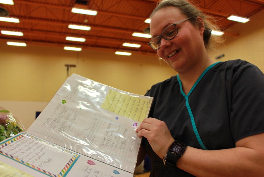 Bev Campbell, a staff member at Queen Elizabeth Elementary School in Kensington, scans the pages of a scrapbook gifted to her after being named on of the 2019 Extra Mile Award recipients.
