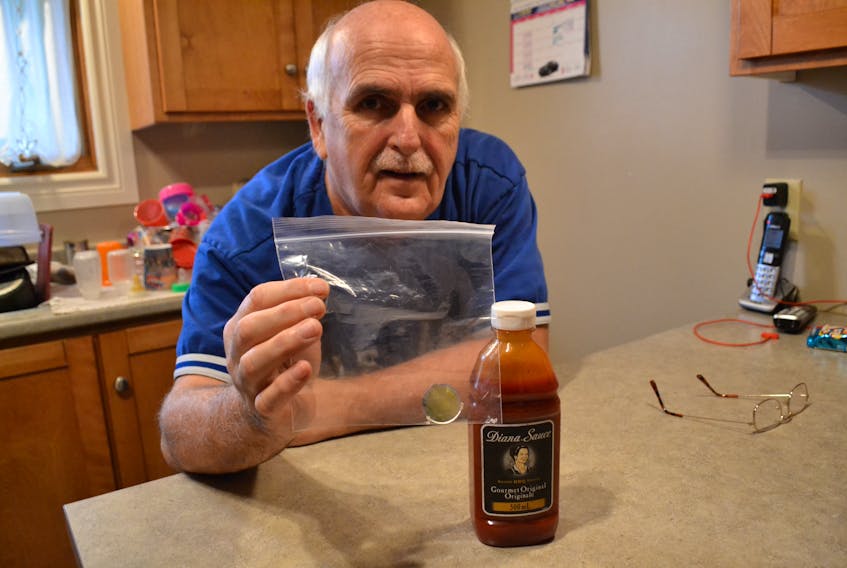 Tignish resident Jerry Cobham displays a bag containing clear fragments resembling glass which he says his partner discovered in the Diana sauce she spread on her plate. (Eric McCarthy/Journal Pioneer)
