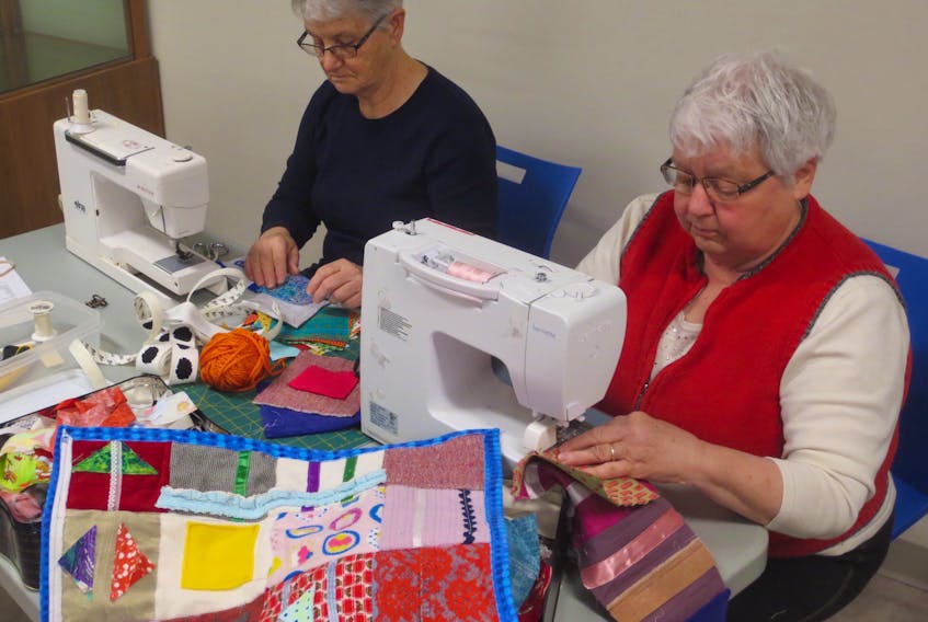 Kay Wall (left) on New Annan and Elaine Burrows of Summerside sit down behind their sewing machines to start putting together their fidget quilts. Brad Collins photo