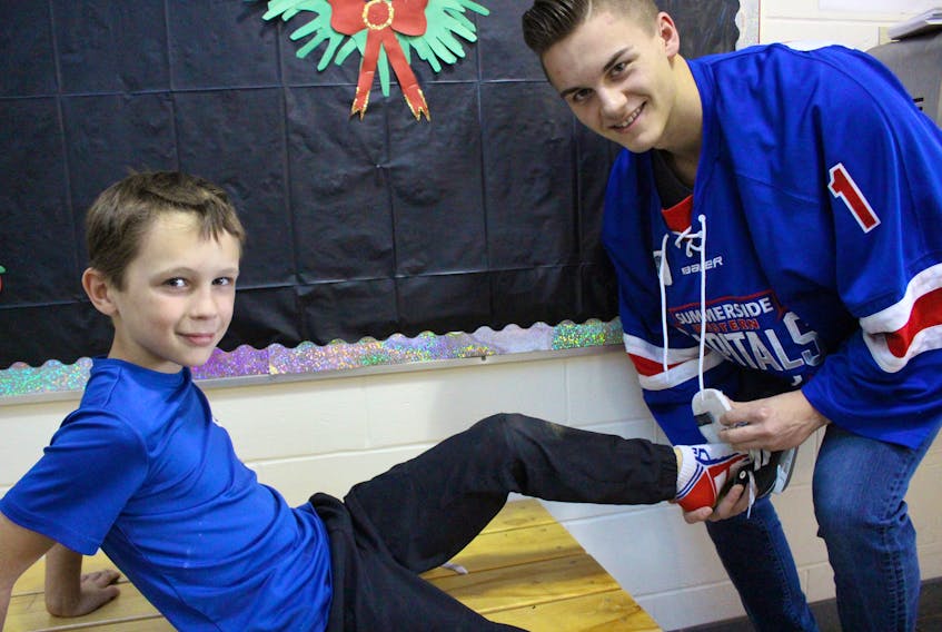 Jack MacDonald, left, gets some help with a skate from Summerside Western Capitals player Brayden Lachance. Lachance and other Summerside Wester Capitals players will participate in the Santa Skate, organized by staff at Athena Consolidated School as a fundraiser for families in the community this Christmas season.