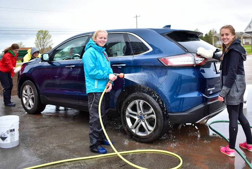 Summerside Dolphin Swim Club members: Ashlyn Meisner, from left, Isabelle Steele and Kate MacKenzie wash cars to raise money for their upcoming trip to Iceland.