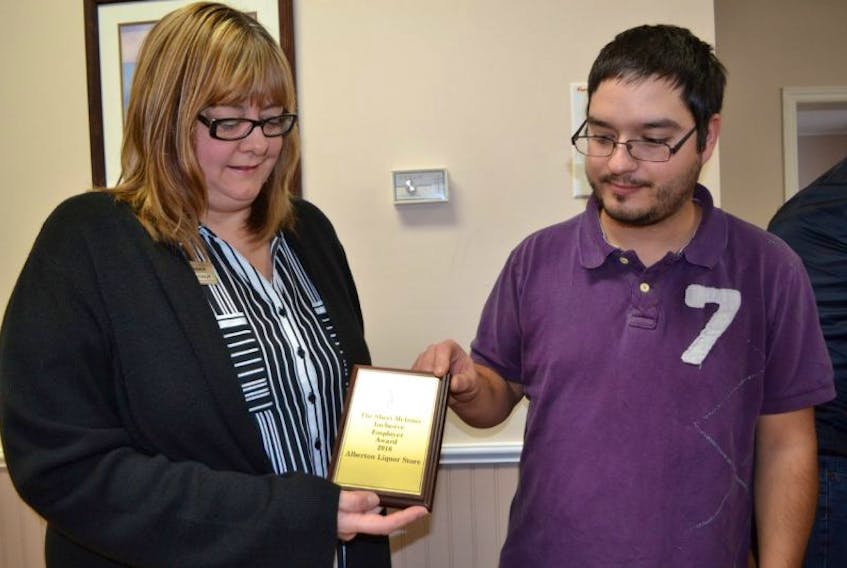 Rhonda Arsenault, manager of the Alberton Liquor Store, shows Jared MacNeill the Sheri McInnis Memorial Inclusive Employer of the Year Award the store received from Community Inclusions. MacNeill, a Community Inclusions client, has been filling a four-hour shift at the store every two weeks for the past five years.