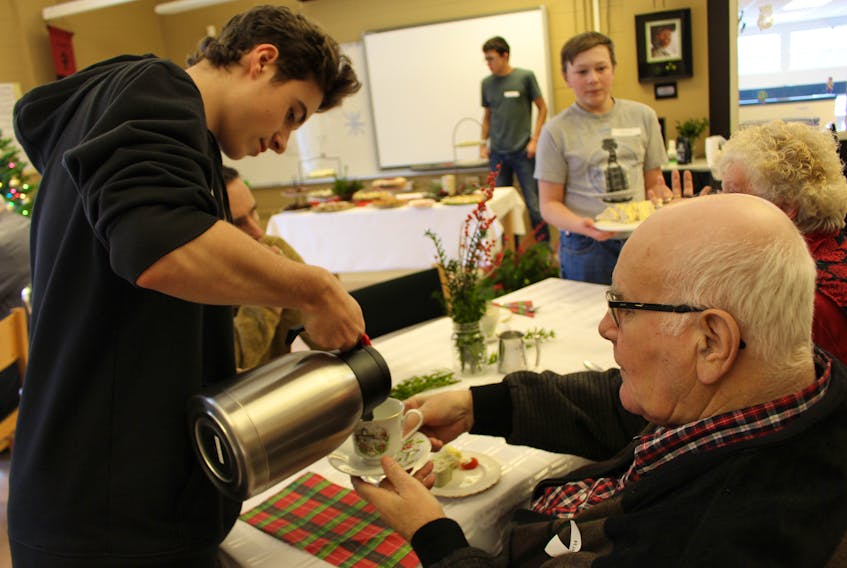 Ethan Boyko, left, serves Ralph MacDonald tea, as Michael Stewart, right makes his way around the table with egg sandwiches. Recently the Grade 10 foods students at KRHS invited community members to learn recipes for the Christmas tea.