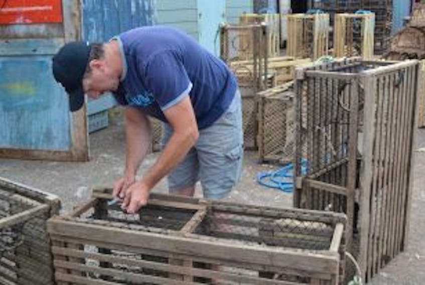 ['Miminegash lobster fisherman Darren Ellsworth replaces the sizzle twine on his lobster traps in preparation for a new lobster fishing season. While his lobster traps will last for approximately seven years, the sizzle twine is a built-in safety and conservation feature to prevent ghost-fishing. The biodegradable twine is designed to fail within a year so that lobsters that get into a lost trap will be able to escape. Fall lobster fishermen in Prince Edward Island’s Lobster Fishing Area 25 will set their gear on August 8. Many of them have already started hauling gear to south side wharves.']